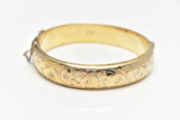 A GOLD PLATED HINGED BANGLE, a hollow gold plated bangle with engraved foliage detail, approximate