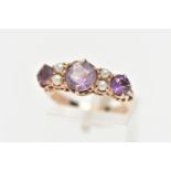 A YELLOW METAL GEM SET RING, designed with three circular cut amethysts, each interspaced with
