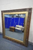 A LARGE WALL MIRROR, the frame constructed from older carved oak timbers, surrounding a gilt border,