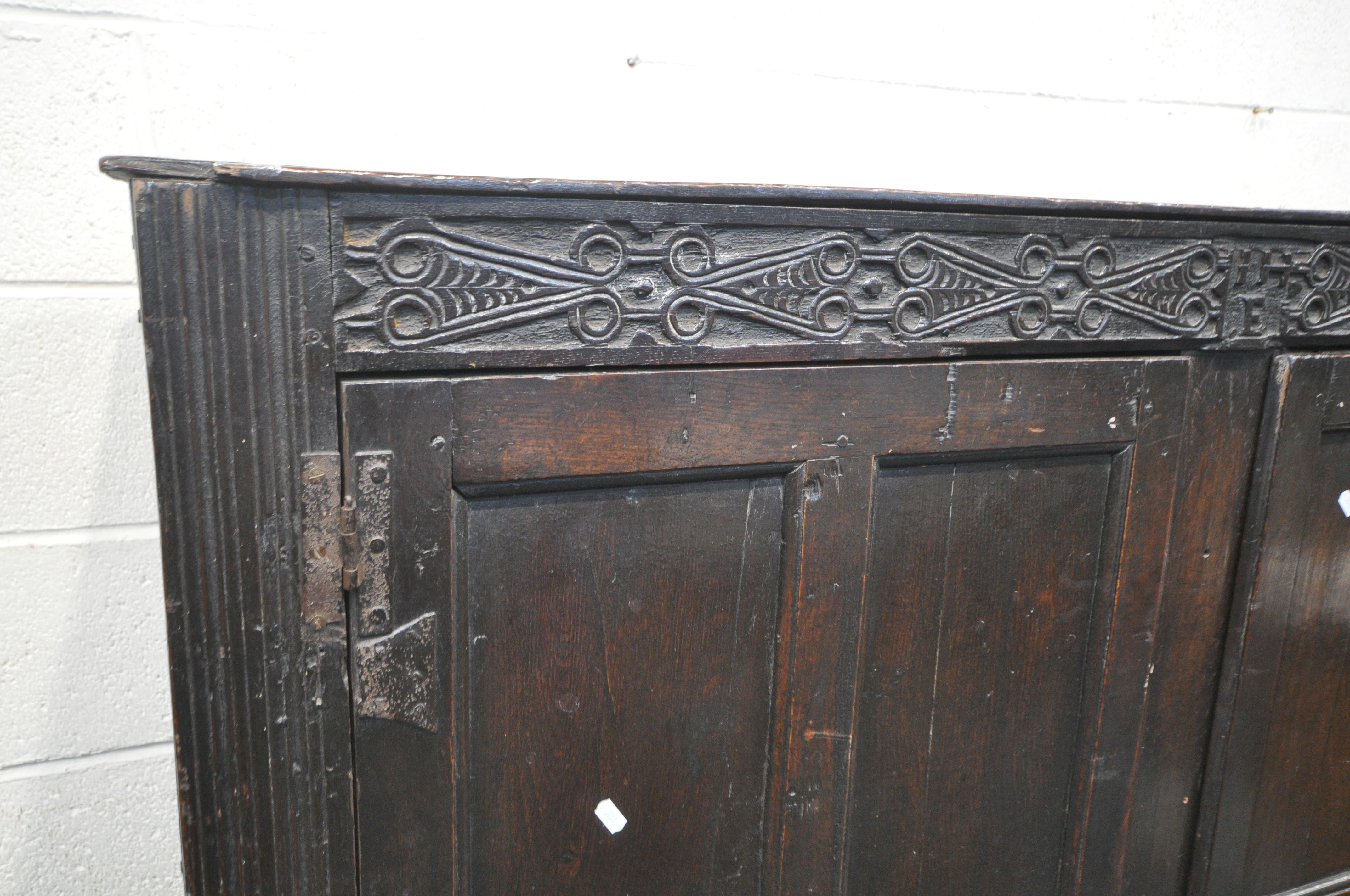 A 17TH CENTURY JOINED OAK CUPBOARD, with a carved top rail, and initialled I.H.E, the double doors - Image 3 of 9