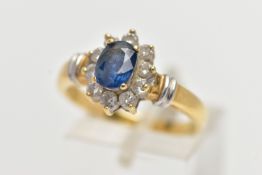 AN 18CT GOLD SAPPIRE AND DIAMOND CLUSTER RING, centering on a raised oval cut blue sapphire,