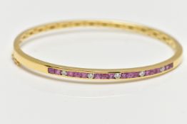 A YELLOW METAL RUBY AND DIAMOND SET HINGED BANGLE, channel set with a row of sixteen square cut pink