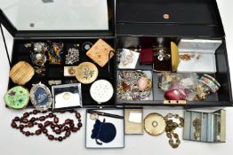 A BLACK TIN AND A DISPLAY CASE WITH COSTUME JEWELLERY, to include paste set brooches, several boxes,