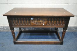 A REPRODUCTION OAK BLANKET CHEST, with a carved front panel, on turned legs, united by a box