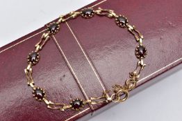 A 9CT YELLOW GOLD GARNET BRACELET, set with seven garnet cabochons, each claw set to a collet mount,
