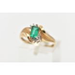 A YELLOW METAL GEM SET RING, designed with a four claw set, rectangular cut emerald, between