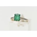 A EMERALD RING, single emerald cut stones, split prong set in white metal flanked with six single