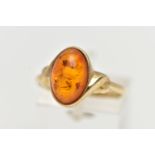 A 9CT YELLOW GOLD AMBER CABOCHON RNIG, collet set with an oval cut amber cabochon, twist detail to