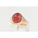 A YELLOW METAL SIGNET RING, an oval carnelian intaglio set within a heavy yellow metal ring,