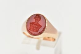 A YELLOW METAL SIGNET RING, an oval carnelian intaglio set within a heavy yellow metal ring,