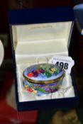 A BOXED MOORCROFT ENAMELS TRINKET BOX, of oval form, decorated with cherries, printed marks to base,