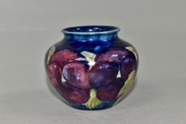 A SMALL MOORCROFT POTTERY BALUSTER VASE, decorated with tube lined purple Pansy pattern on a dark