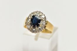 A YELLOW METAL SAPPHIRE AND DIAMOND CLUSTER RING, centering on an oval cut deep blue sapphire, in