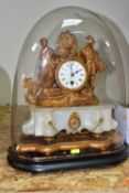 A GILT FRENCH ROCOCO STYLE MANTLE CLOCK, on an ebonized stand with a large glass dome, the figural