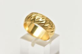 A WIDE YELLOW METAL TEXTURED BAND, approximate band width 7.6mm, stamped 18ct, ring size centre N,