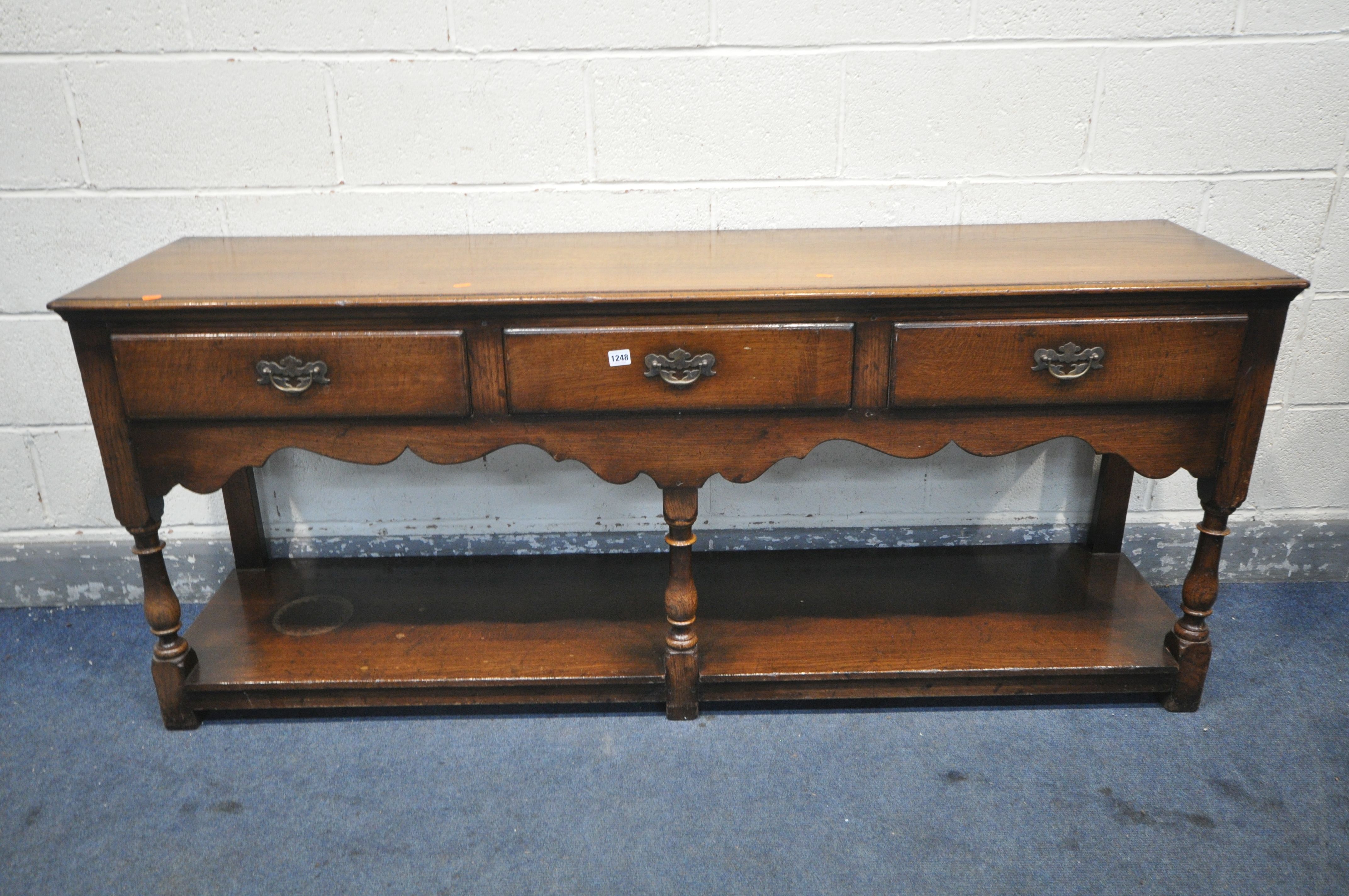 A REPRODUCTION OAK DRESSER BASE, with three frieze drawers, on turned front legs, united by an under