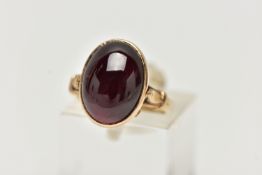 A 9CT YELLOW GOLD GARNET SINGLE STONE RING, the oval garnet cabochon, within a collet setting, to