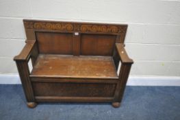 A 20TH CENTURY OAK MONKS BENCH, with scrolled detailing to top, open armrests, a hinged storage lid,