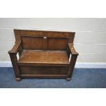 A 20TH CENTURY OAK MONKS BENCH, with scrolled detailing to top, open armrests, a hinged storage lid,