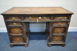 AN EARLY TO MID 20TH CENTURY OAK KNEE HOLE DESK, with a tanned leather writing surface, nine