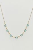 A MID 20TH CENTURY YELLOW METAL NECKLACE, set with seven pale blue square cut pastes, each claw