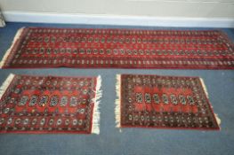 A 20TH CENTURY RED GROUND TEKKE CARPET RUNNER, length 302cm x 82cm, and a pair of red ground tekke