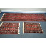 A 20TH CENTURY RED GROUND TEKKE CARPET RUNNER, length 302cm x 82cm, and a pair of red ground tekke