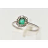 A WHITE METAL, EMERALD AND DIAMOND CLUSTER RING, centering on an emerald cut emerald, in a