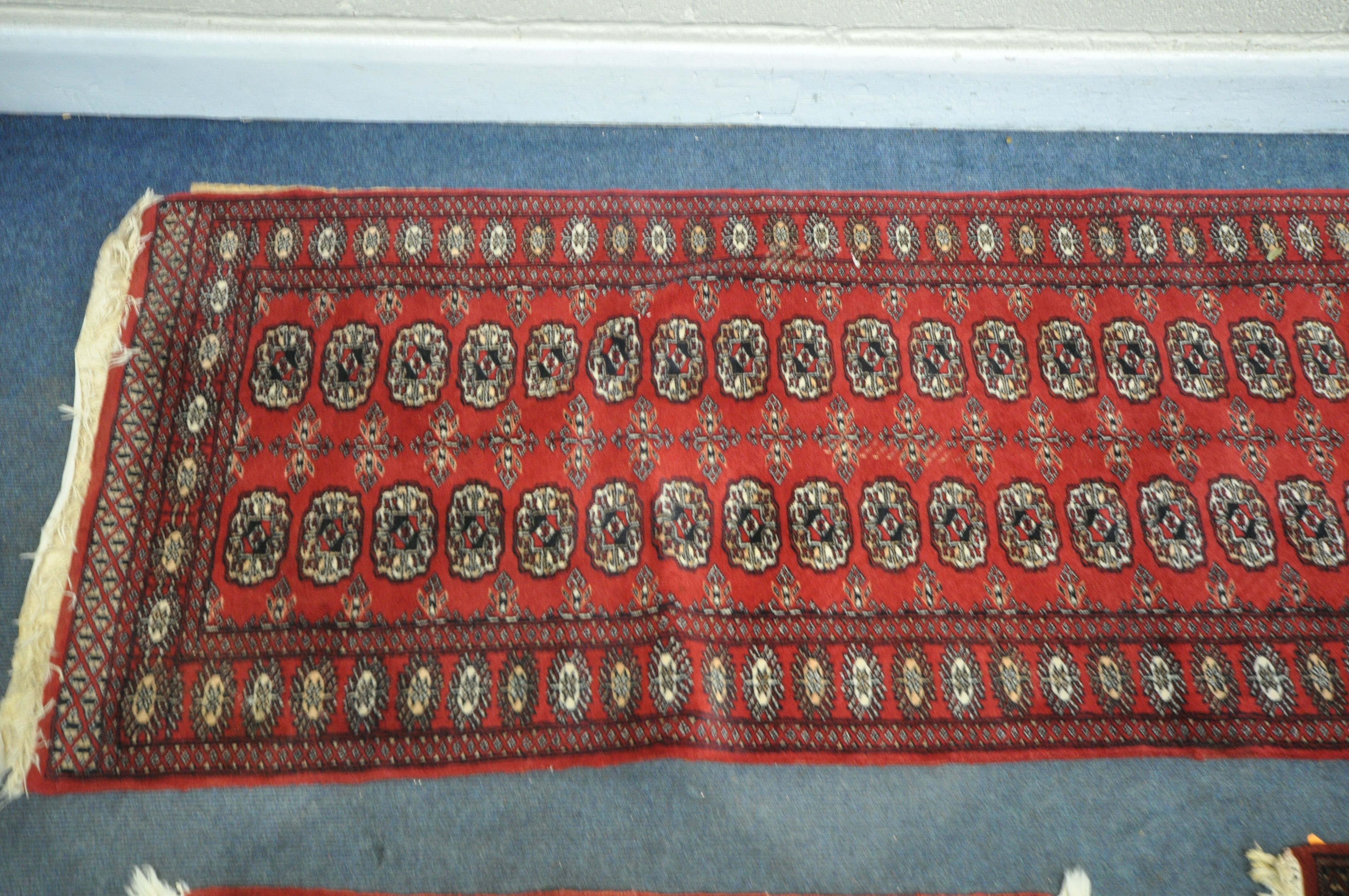 A 20TH CENTURY RED GROUND TEKKE CARPET RUNNER, length 302cm x 82cm, and a pair of red ground tekke - Image 2 of 5