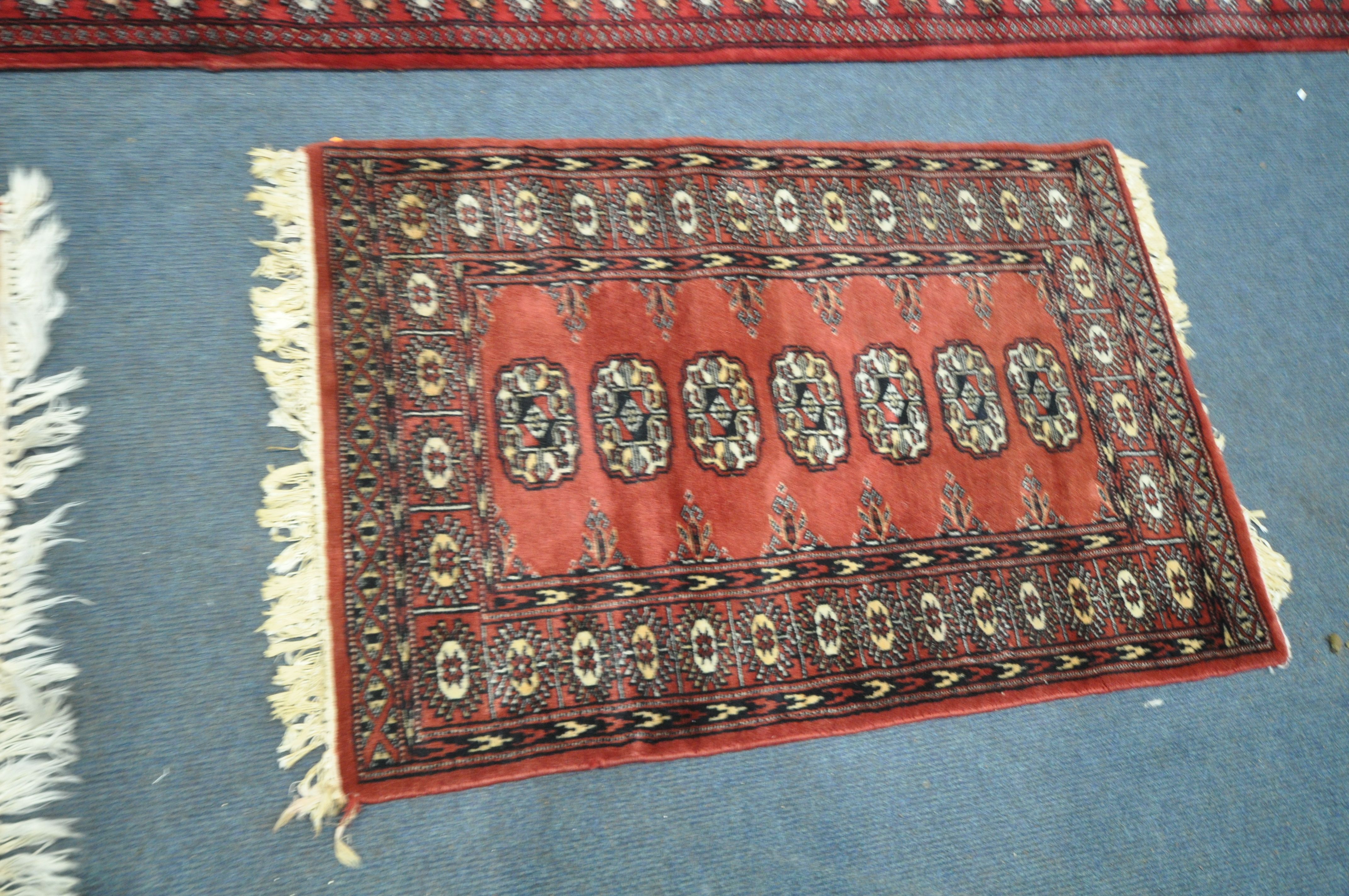 A 20TH CENTURY RED GROUND TEKKE CARPET RUNNER, length 302cm x 82cm, and a pair of red ground tekke - Image 5 of 5