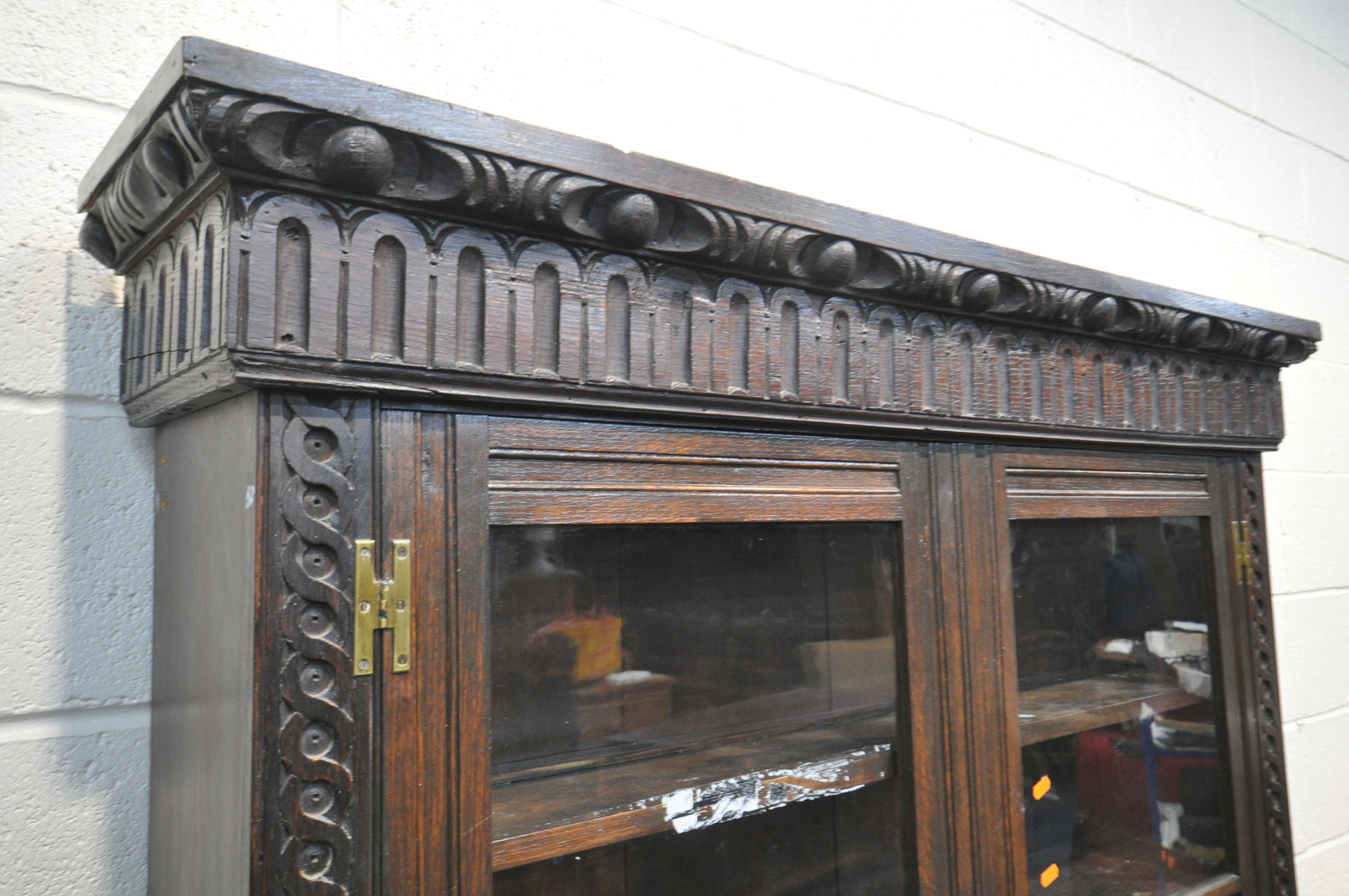 A CARVED OAK BOOKCASE, with double glazed doors that's enclosing three adjustable shelves, on a base - Image 2 of 4