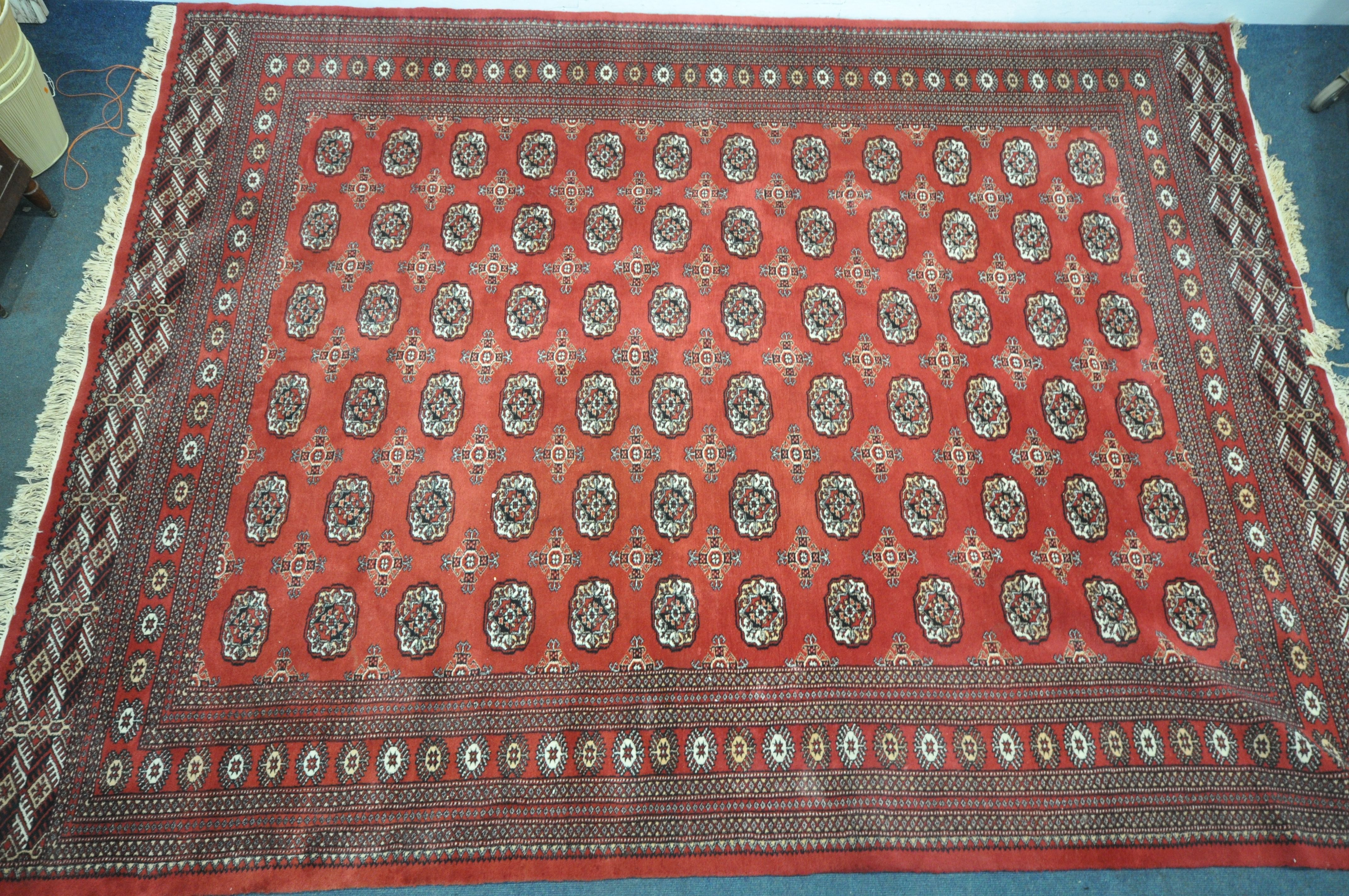 A LARGE 20TH CENTURY RED GROUND TEKKE RUG, 367cm x 278cm