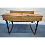 A LATE 19TH/EARLY 20TH CENTURY OAK TWIN SCHOOL DESK, with a cast iron frame, two ink well slots, and