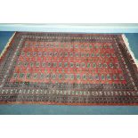 A 20TH CENTURY RED GROUND TEKKEE RUG, 248cm x 164cm