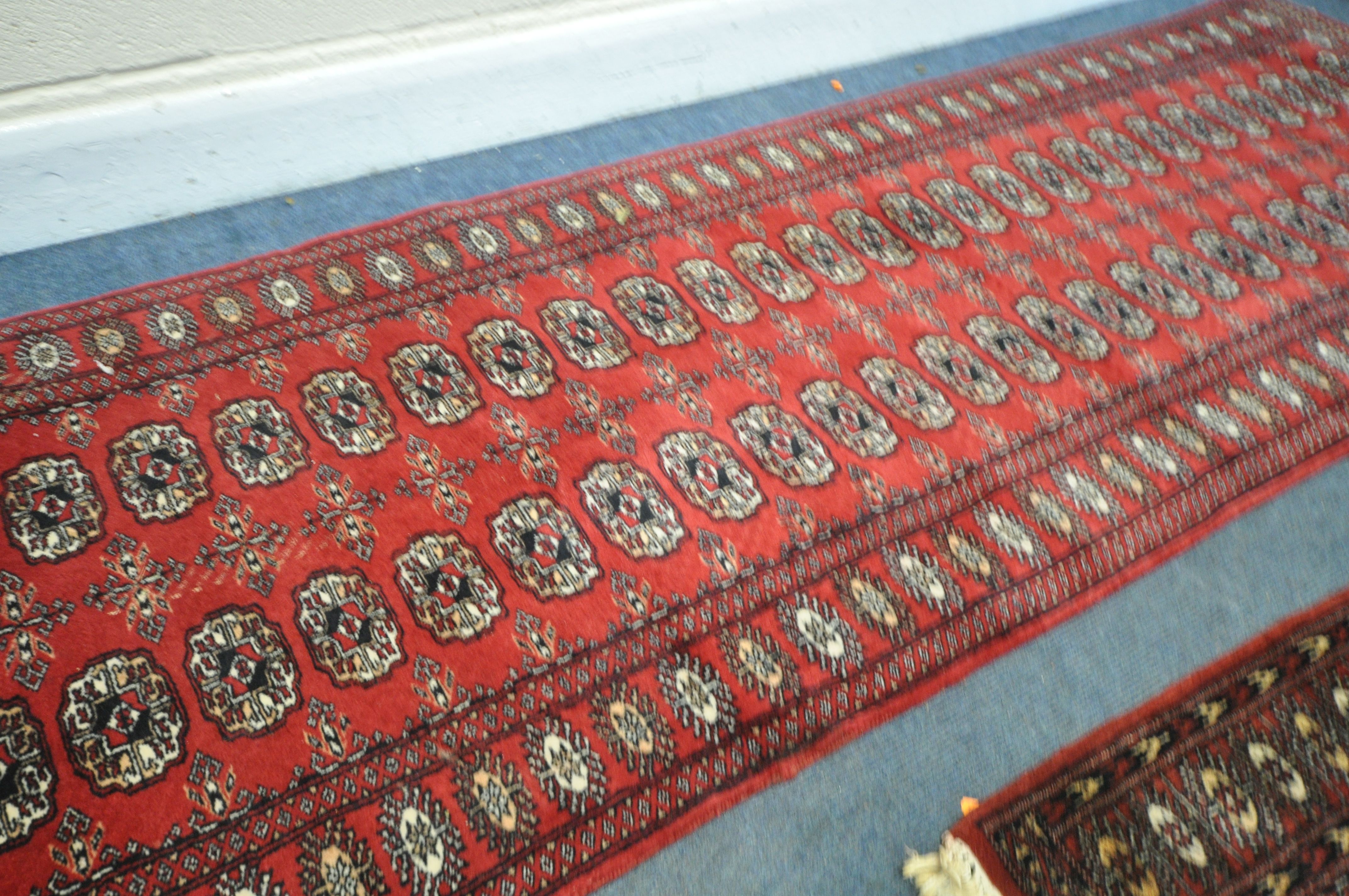 A 20TH CENTURY RED GROUND TEKKE CARPET RUNNER, length 302cm x 82cm, and a pair of red ground tekke - Image 3 of 5