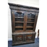 A CARVED OAK BOOKCASE, with double glazed doors that's enclosing three adjustable shelves, on a base