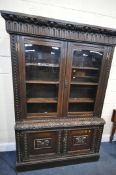 A CARVED OAK BOOKCASE, with double glazed doors that's enclosing three adjustable shelves, on a base