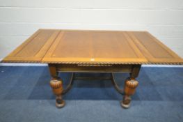 AN EARLY 20TH CENTURY OAK DRAW LEAF DINING TABLE, on acorn legs, united by a shaped stretcher,