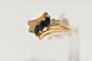 A YELLOW METAL GEMSET DRESS RING, three marquise cut sapphires accented with four single cut