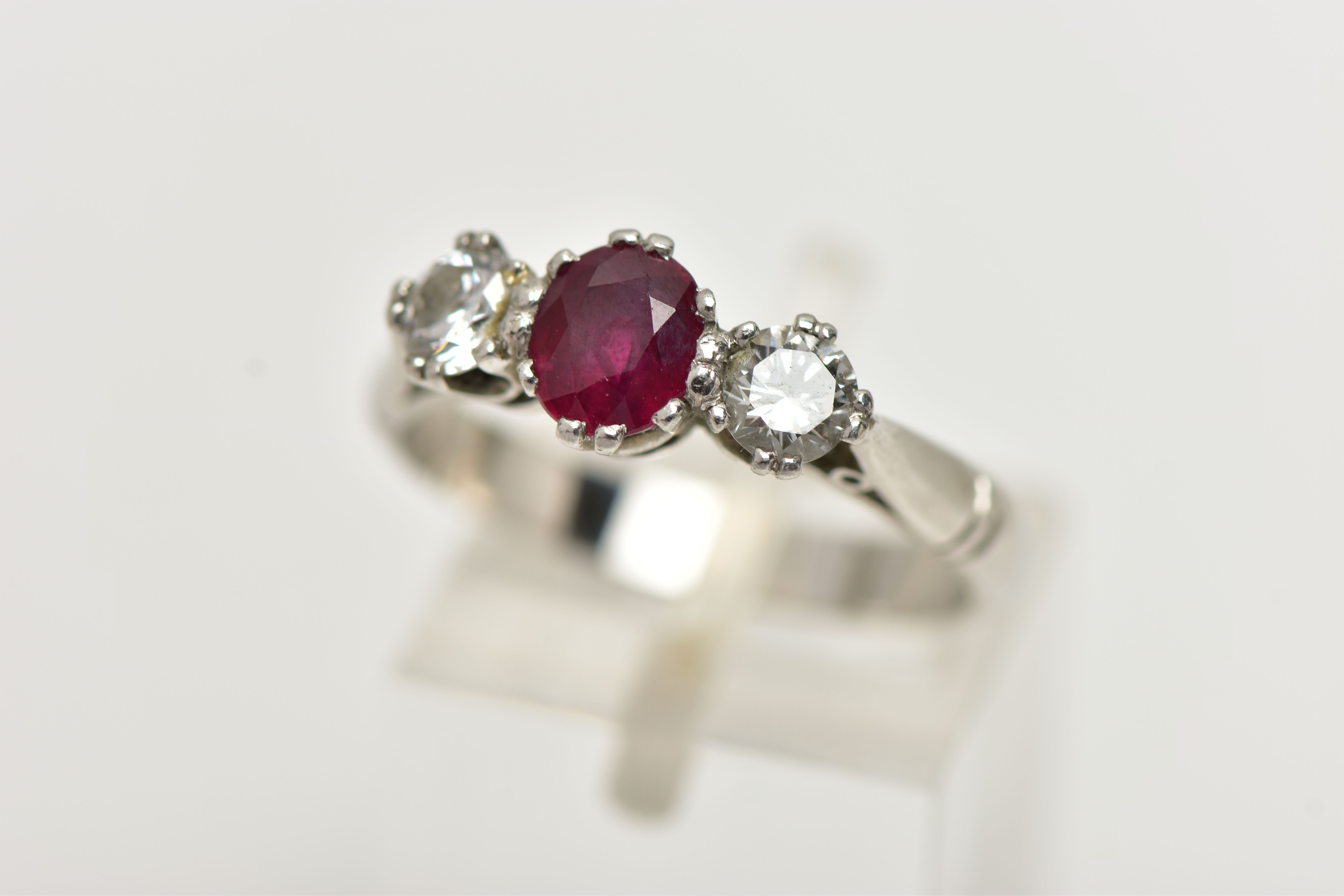 A PLATINUM RUBY AND DIAMOND THREE STONE RING, centering on an oval cut ruby,