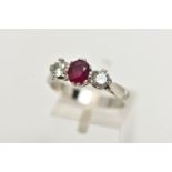 A PLATINUM RUBY AND DIAMOND THREE STONE RING, centering on an oval cut ruby,