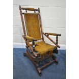 AN EDWARDIAN WALNUT AMERICAN ROCKING CHAIR (condition:-fabric worn and fraying)