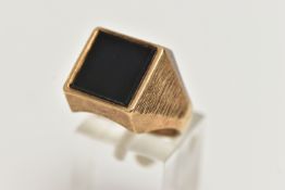 AN ONYX SIGNET RING, designed as a square onyx panel, to the tapered textured shoulders, onyx