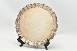 A GEORGE V SILVER SALVER OF CIRCULAR FORM WITH PIE CRUST RIM, engraved narrow border, on three