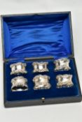A CASED SET OF SIX GEORGE V SILVER NAPKIN RINGS, of circular form cast with scrolled rims, maker's