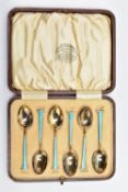A CASED SET OF SIX GEORGE V SILVER GILT AND ENAMEL COFFEE SPOONS, the handles engine turned and