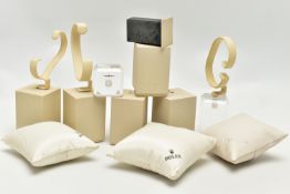 A SELECTION OF WATCH DISPLAY STANDS AND CUSHIONS, comprising five cream stands each with a Rolex