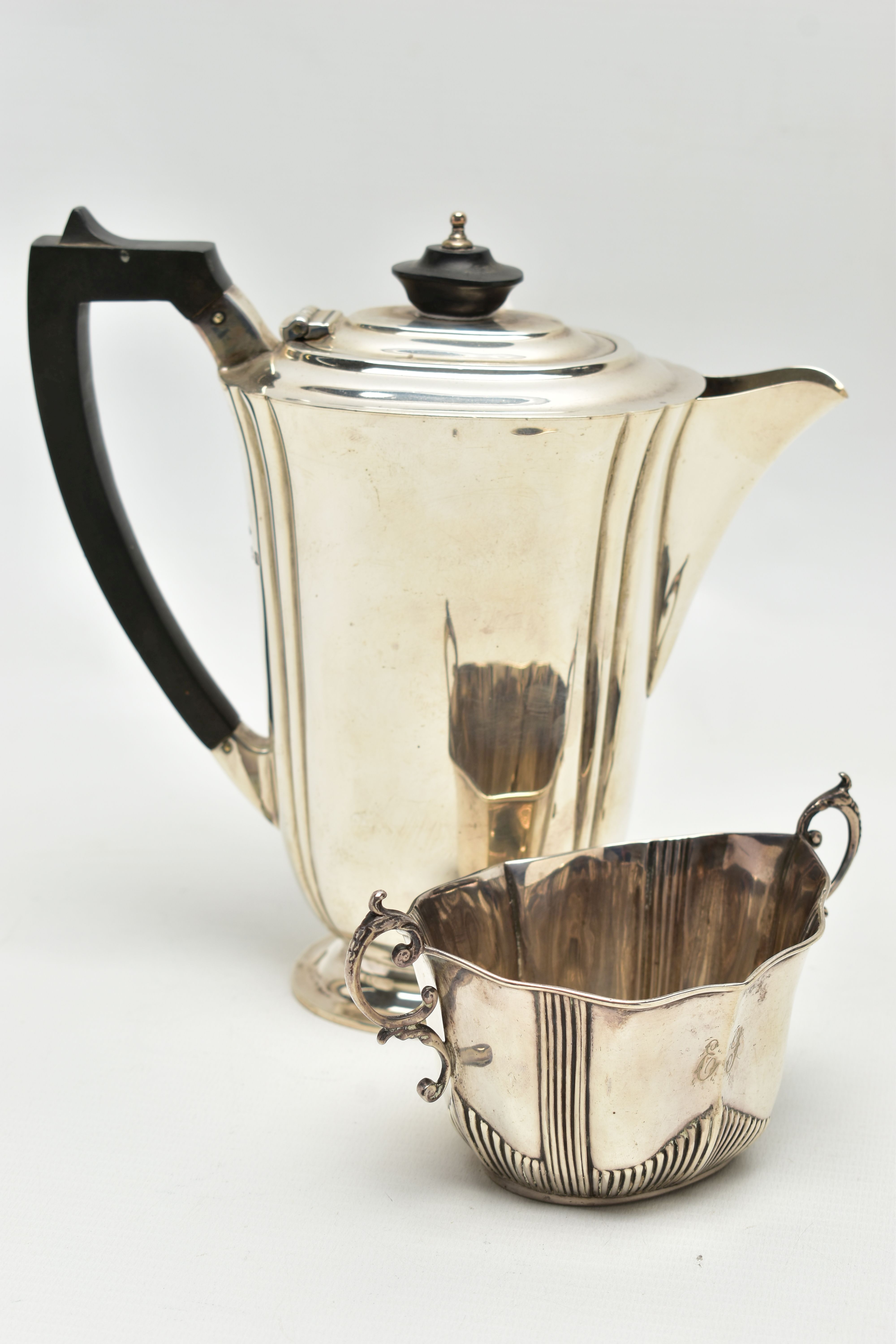 A GEORGE V SILVER HOT WATER JUG AND A LATE VICTORIAN TWIN HANDLED SUGAR BOWL, the hot water jug of