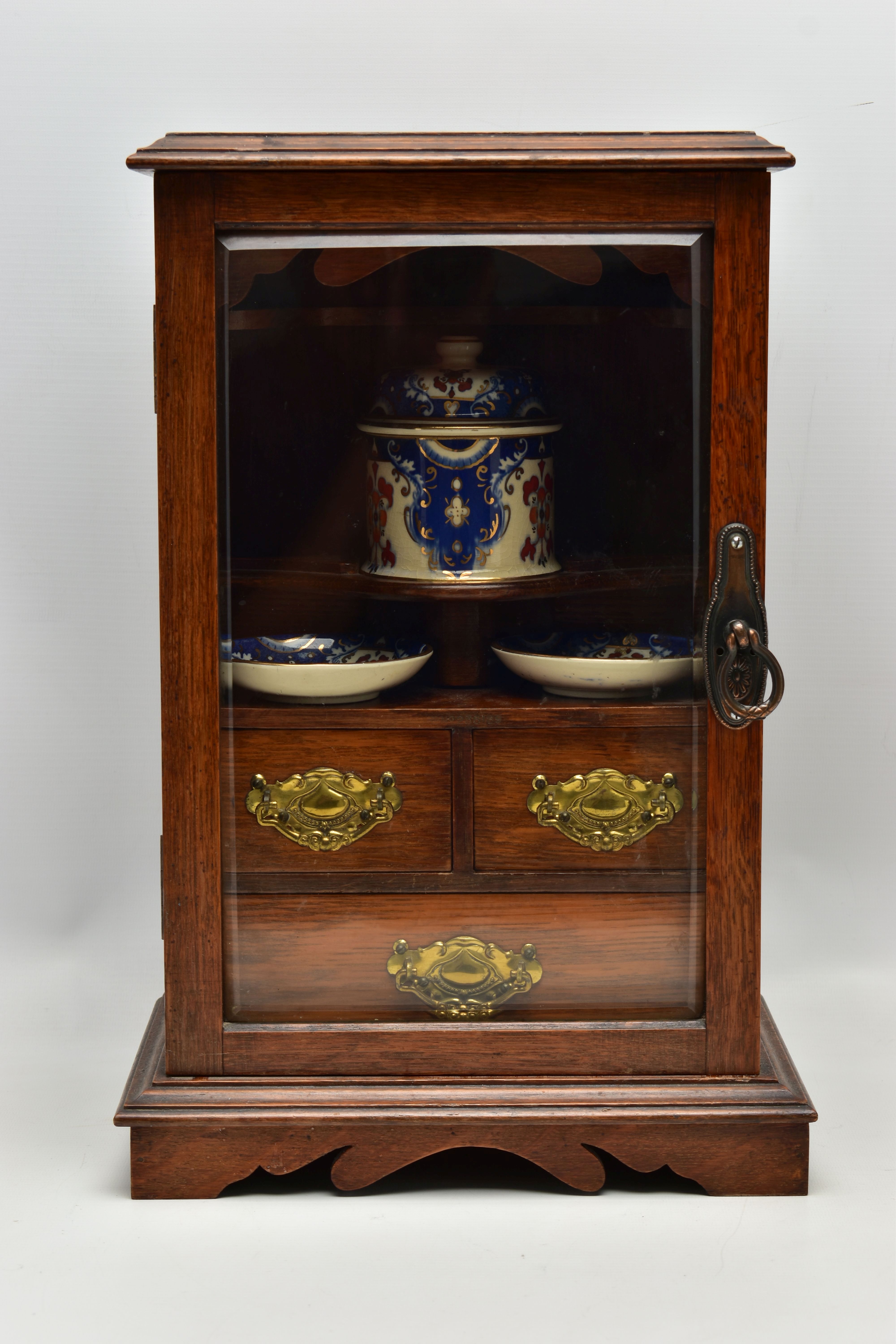 A LATE VICTORIAN OAK CASED SMOKERS CABINET, the bevel edged glazed door opening to reveal a pipe