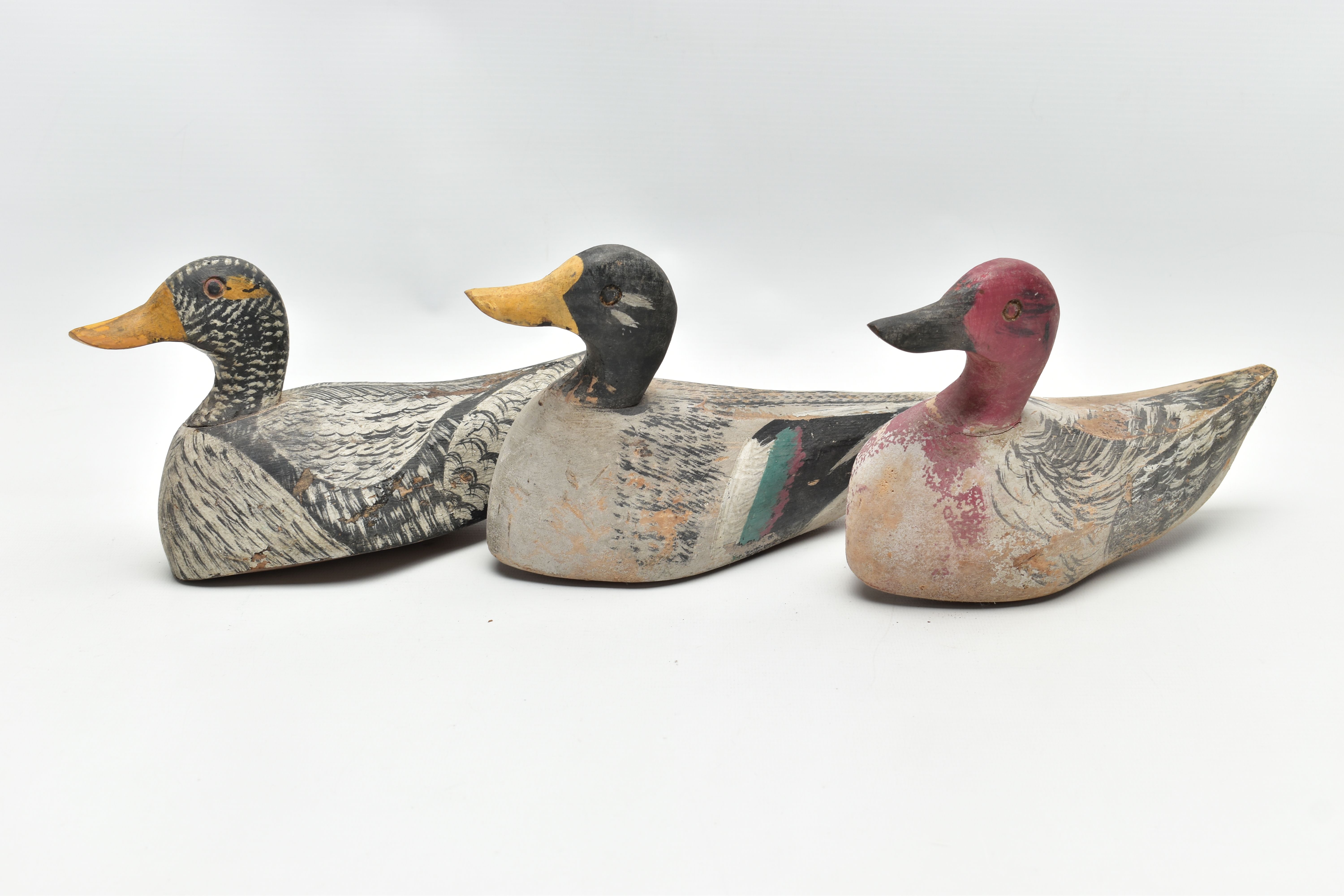 THREE CARVED WOODEN DECOY DUCKS WITH POLYCHROME PAINTED DECORATION, impressed circle eyes,